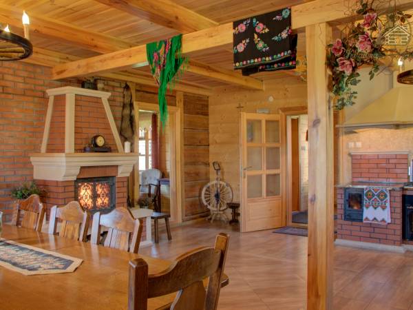 Duży salon w którym znajduję się kominek, skórzana kanapa i stół na 12 osób