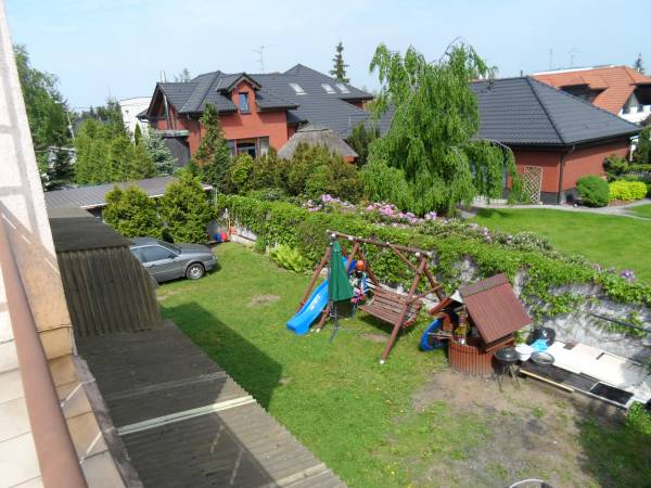 Widok ogrodu, miejsca wypoczynku gości, grill, huśtawka, zjeżdżalnia dla dzieci, huśtawka dla dzieci i dorosłych.