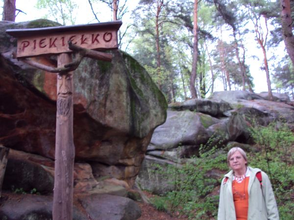 na szlaku: Rezerwatu przyrody nieożywionej "Skamieniałe Miasto". Pod dekoracyjną deską szyldu : całkiem pogodna twarz / oblicze ducha tego miasta - przy temacie