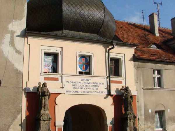 BRAMA  DO  OPACTWA  ZNAJDUJE  SIĘ  W  SZEREGU  KAMIENICZEK  GŁÓWNEJ  ULICY  HENRYKOWA.
Henryków jest starą klasztorną wsią, u podnóża Wzgórz Strzelińskich Opac