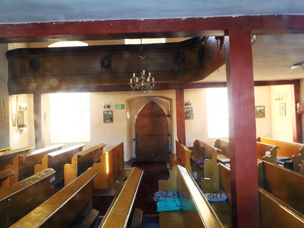 Fragment wnętrza kościoła z widoczny fragmentem empory - zdjęcie przez szybe