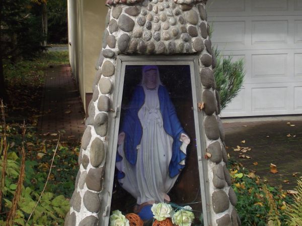kapliczka przydomowa, w niszy z figurką Matki Boskiej. Zwieńczenie bryły / formy sugeruje wyobrażenie Matki Boskiej Królowej Polski. Kapliczki stanowią pomniki