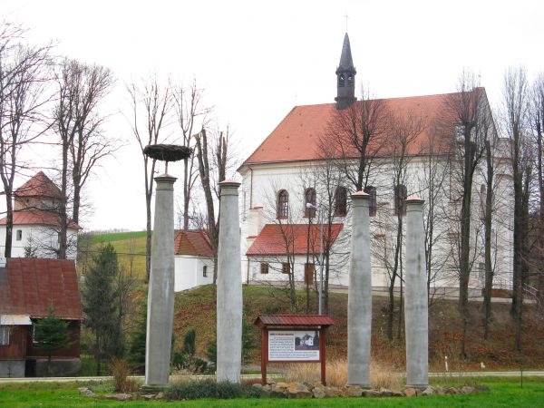 wzgórze z kościołem, dzwonnicą i kaplicą nagrobną, na 1-szym planie kolumny  portyku spalonego w 1945r. dworu. Dzwonnica bramna o charakterze obronnym, strzegąc