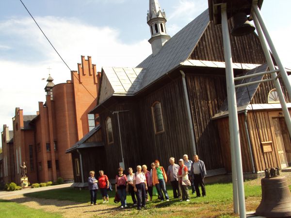 przed kościołami : nowym i starszym, drewnianym budowanym w latach 30-tych XX wieku, modrzewiowym, zabytkowym - współcześnie służącym jako kaplica przedpogrzebo