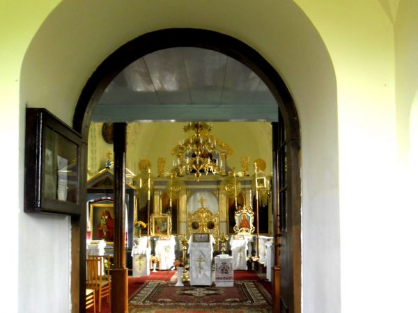 Wnętrze cerkwi widziane przez otwarte drzwi, ale zamkniętą kratę.