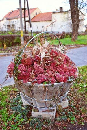 Kosz z kwiatami obok figury św Jana Nepomucena