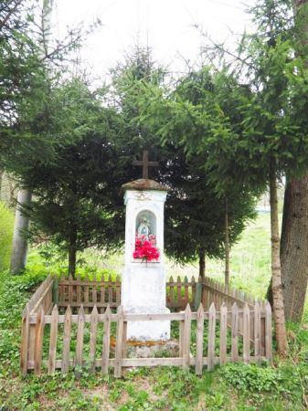 kapliczka przydrożna, otoczona drewnianym płotkiem, murowana, zabytkowa, znak obecności chrześcijaństwa i ludowej pobożności.