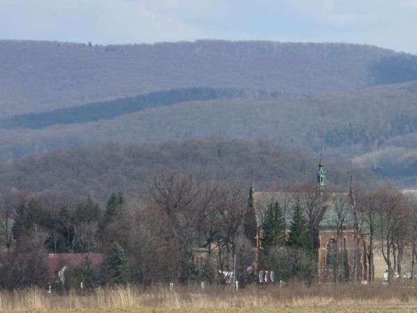 Widok na wieś ze " Wzgórz Szczodrych":  kościół i część dachów obiektów klasztoru Zgromadzenia Sióstr Franciszkanek Rycerstwa Niepokalanej. Dalej - w słabo wido