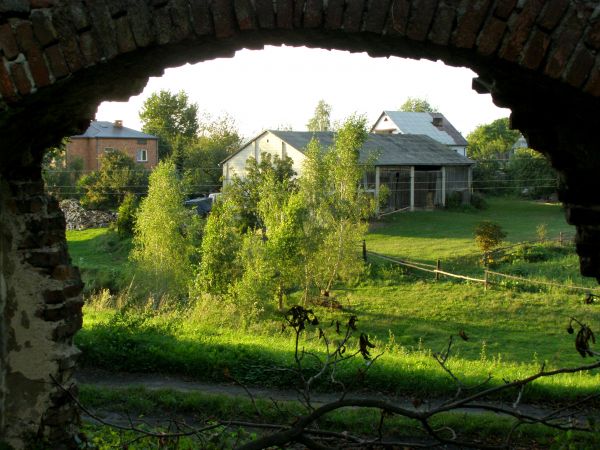 ZAWIEPRZYCE
***
Widok zabudowań wiejskich przez wyłom w murze pałacowym.