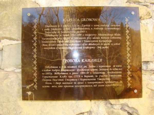 na ścianie kaplicy grobowej : tablica z informacją w językach polskim i ukraińskim.