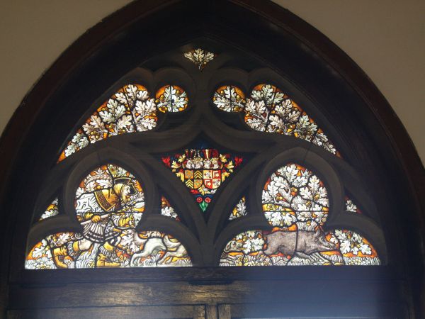 witraż nad drzwiami - w centralnym polu dwa herby, poniżej scena myśliwska - pogoń z psem za dzikiem, dużo wici roślinnej w postaci liści dębu.