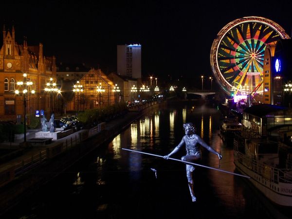 Bydgoszcz - widok z mostu Jerzego Sulimy-Kamińskiego na zawieszony nad Brdą pomnik "Przechodzący przez rzekę". W głębi z lewej neogotycki budynek Poczty Głównej