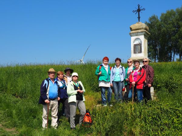przed krzyżem wśród pól - przy tzw. gościńcu, bo tą drogą niegdyś dojeżdżali m.in. kuracjusze z dworca PKP we Wróbliku Szlacheckim do kurortu w Iwoniczu Zdroju
