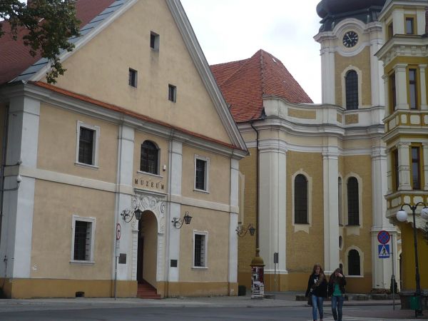 Na Placu 1 Maja budynek poklasztorny a w nim muzeum miasta Krotoszyn na pierwszym planie dalej kościół Św. Piotra i Pawła.
