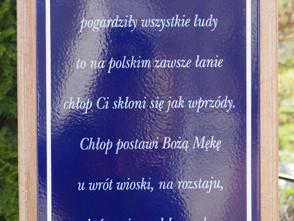 tablica z przesłaniem - na pionowej belce krzyża przydrożnego, droga w lewo wiodła będzie do " kościółka pod lasem" a w nim obraz Władysława Lisowskiego z 1926r