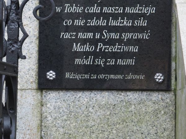 tablica na murku okalającym statuę Matki Boskiej Przedziwnej - przy Pawilonie nad źródłami.