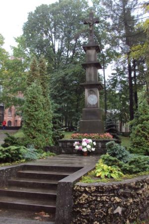 krzyż kamienny na wysokim wieloczłonowym postumencie - przy wejściu bramą główną na Kalwarię Piekarską, n/z po lewej widoczny fragment kalwaryjskiego kościoła.