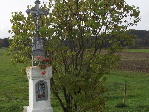 ślady wiary i kultury żyjących tu niegdyś - później zazwyczaj przesiedlonych - krzyż na postumencie a w niszy oszklonej figura Matki Boskiej a niżej złożone med