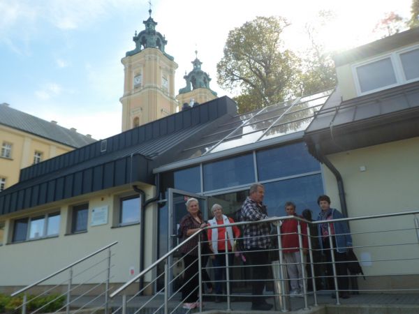 tu biuro obsługujące ruch turystyczny, sklep z pamiątkami i kawiarnia, dalej widać wieże bazyliki.