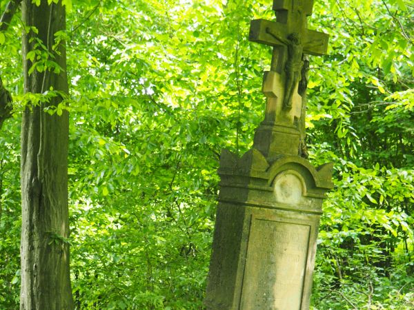 krzyż na kamiennym cokole - pomnik nagrobny o bogatej ornamentyce, na  cmentarzu przycerkiewnym.