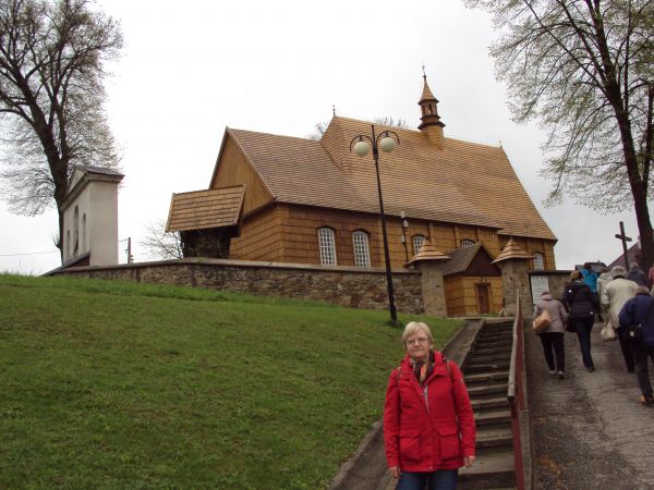 przed zabytkowym, stylowym, modrzewiowym kościołem.