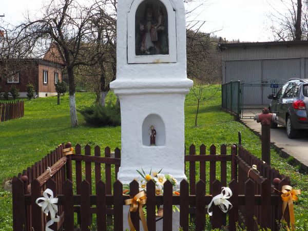 krzyż przydrożny, zabytkowy, na wysokim murowanym postumencie z dwoma w pionie niszami, w płycinie niżej : figurka przedstawiająca św. Antoniego z Dzieciątkiem,