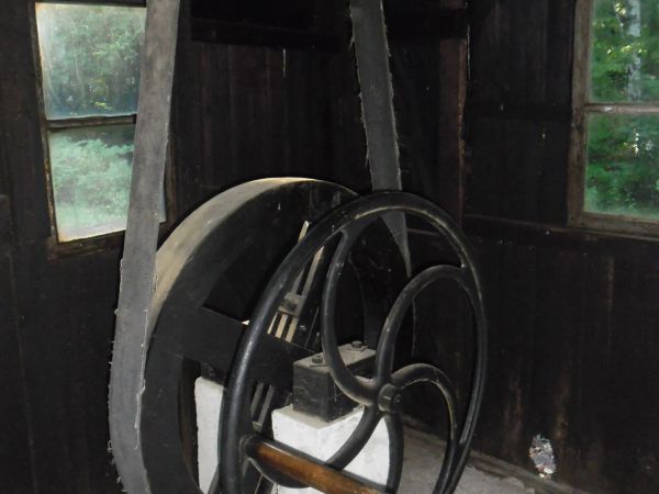 Ręczny napęd przekładni pasowej uruchamiającej maszyny w warsztacie ślusarskim.