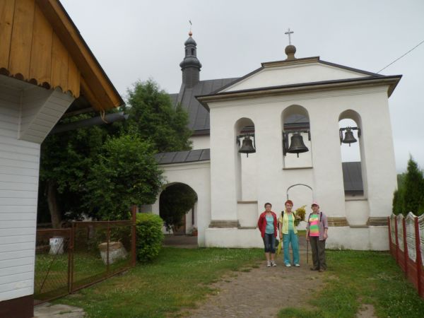 przed dzwonnicą, jej dach ze ściętym szczytem zwieńczonym kulą z osadzonym krzyżem,  po lewej bramka na cmentarz przykościelny - nieużytkowany, kościół otoczony