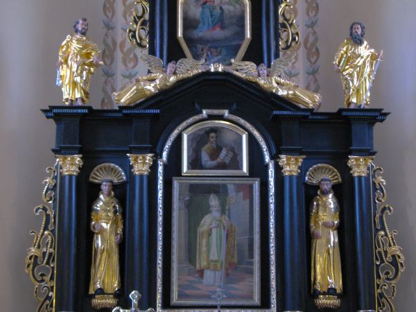 między kolumnami w hemisferycznie zamkniętych niszach rzeźby śś. Franciszka z Asyżu i Antoniego Padewskiego, po bokach rzeźby śś. Piotra i Pawła.