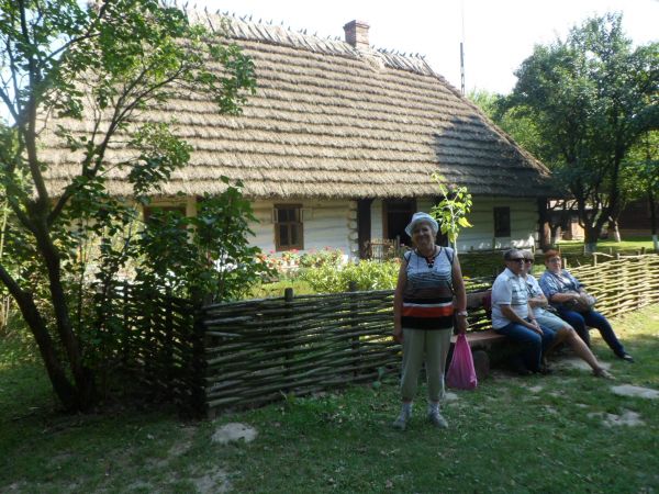Chałupa Kmieca - ładny płotek pleciony z wierzbowych gałęzi - inaczej : jest to płot pleciony tzw. kiełbaskami, obfite kwiecie w ogródku, przy płotku bez - lila