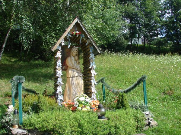 Zadbana i bardzo interesująca figurka przydrożna z okolic Wisły (Beskid Śląski).W swym wystroju nawiązuje do tradycji ludowych górali żywieckich. Pod daszkiem w