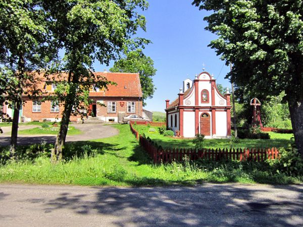 Wieś Kominki-widok na zabytkową neobarokową kaplicę z 1843 r. Wieś położona około 6,5 km.na zachód od Reszla przy drodze nr.593