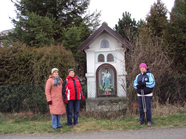 na zdjęciu: przed/obok kapliczki przydrożnej zabytkowej, z figurą Matki Boskiej z Dzieciątkiem - w niszy głównej - za szkłem oraz wyżej w płycinach za taflami z