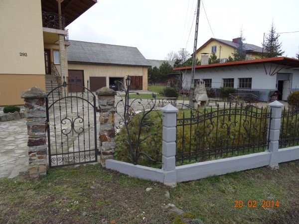 przy bramce: osobny panel / element ogrodzenia z motywem roślinnym - dzieło pochodzi z tej pracowni kowalskiej.