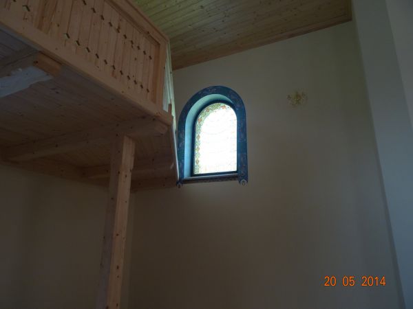 fragment parapetu chóru - wspartego obelkowaniem oraz okno z witrażem wici roślinnej w półzamkniętym koliście otoku, obok kinkiet - dwugniazdowy. Podczas konsek