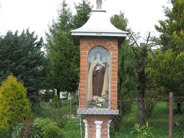 kapliczka przydomowa z figurą świętej w oszklonej niszy, słupowa, z balaskami, dwukondygnacyjna, zwieńczona metalowym krzyżem nad kopułą a w niej pozorna przesz