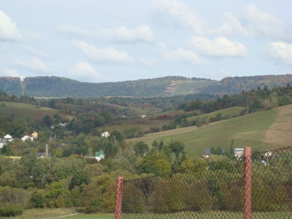 widok ze wzgórza Lachawa, w dolinie w zadrzewieniu pomnik przyrody "Wodospad na rzece Olszance".