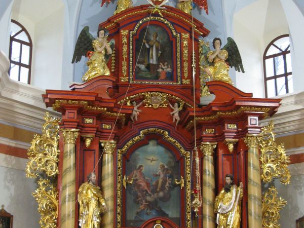 ołtarz główny kościoła - z zasuwą / obrazem przedstawiającym Trójcę Świętą, powyżej w zwieńczeniu: św. Mikołaj.