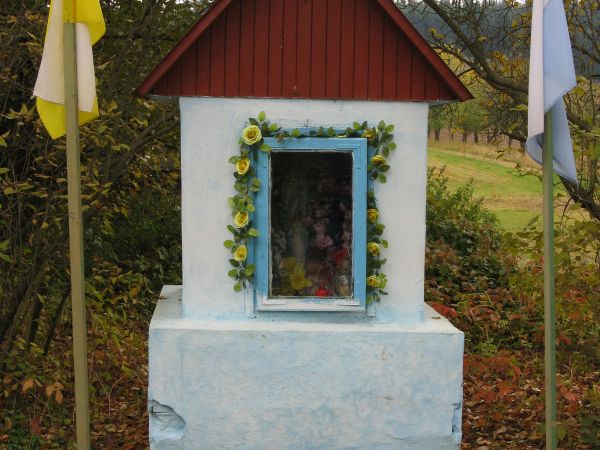 w centrum wsi: rekonstrukcja XIX wiecznej kapliczki, której oryginał przewrócił się i rozsypał u progu XXI wieku.