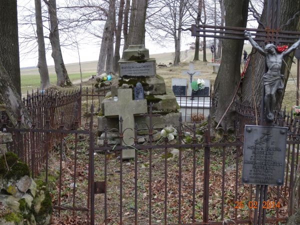 ogrodzone płotkiem miejsce pochówków - z postumentem nagrobnym, obeliskiem zwieńczonym krzyżem i tablicą inskrypcyjną. Tylko wierne kwiecie na wiosnę mogiłę będ