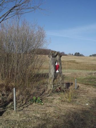 Figurka Chrystusowa w płycinie postumentu kamiennego, tam niegdyś krzyż był osadzony, może kuty żeliwny o bogatej ornamentyce, może ? ... - nie przetrwał powoje