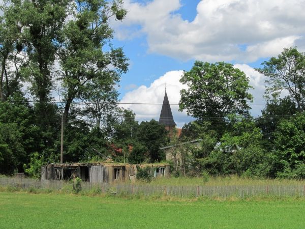 Ruiny spalonej chaty i dalej wieża kościoła