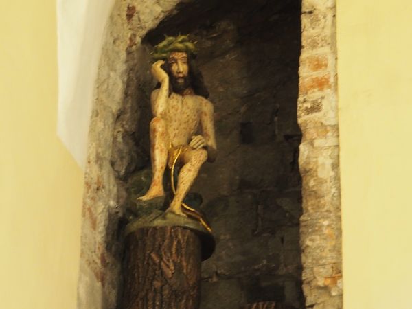 Chrystus Frasobliwy - rzeźba umieszczona w niszy wiekowych murów przedsionka kościoła.