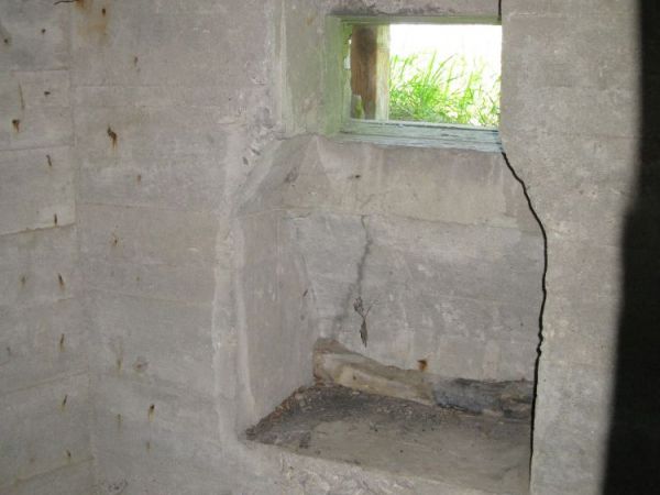 Widok z wnętrza izby bojowej załogi Schronu nr 2. na stanowisko strzelnicy karabinu maszynowego zachodniego tradytora...