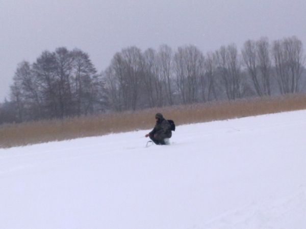 Zasypane śniegiem jezioro Łąke, a na nim wędkarze podlodowi.