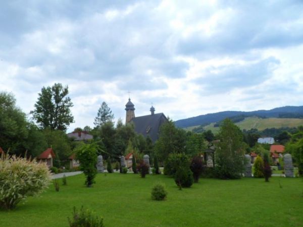 widok na nowy kościół i zalesiona zbocza pasma Beskidu Sądeckiego.