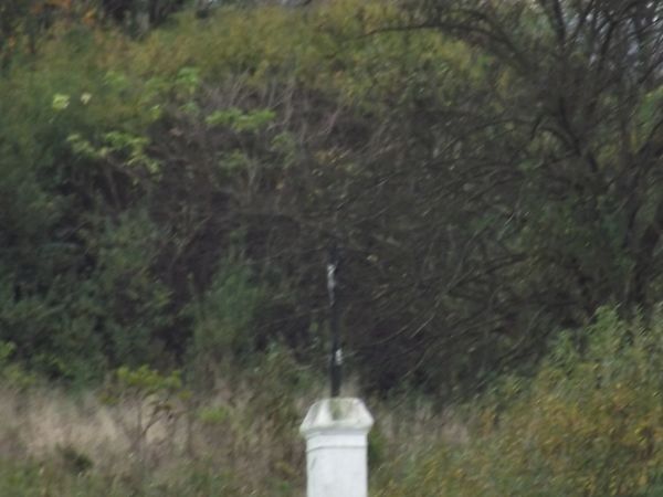 krzyż metalowy / żeliwny na cokole, śródpolny - dzisiaj, kiedyś: przydrożny, bo droga do przysiółka Roztoka prowadziła, nazwa została / krzyż został - jeno ludz