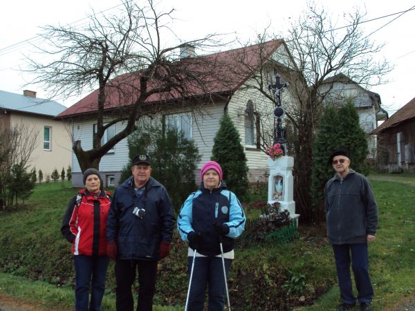 przy krzyżu przydrożnym na cokole z figurką Matki Boskiej w niszy cokołu.