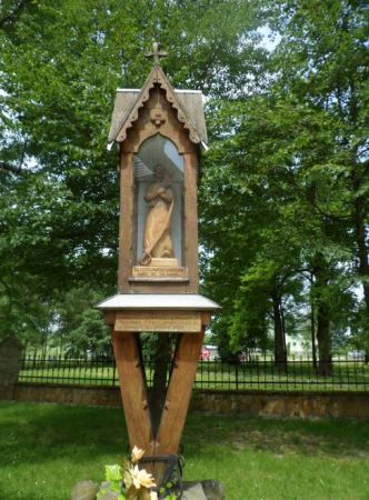 kapliczka przy kościele - w oszklonej niszy drewniana rzeźba przedstawiająca św. Wojciecha - patrona kościoła i parafii.