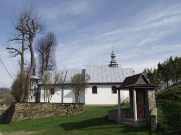 Stacja Drogi Krzyżowej a dalej kościół z murem kamiennym od przodu.